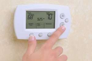 a hand touching a thermostat