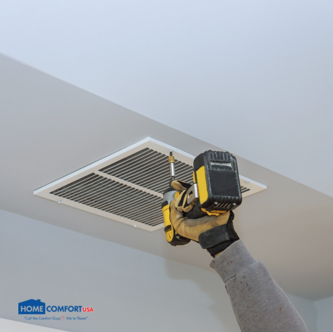 A tech drilling a filter frame into a ceiling