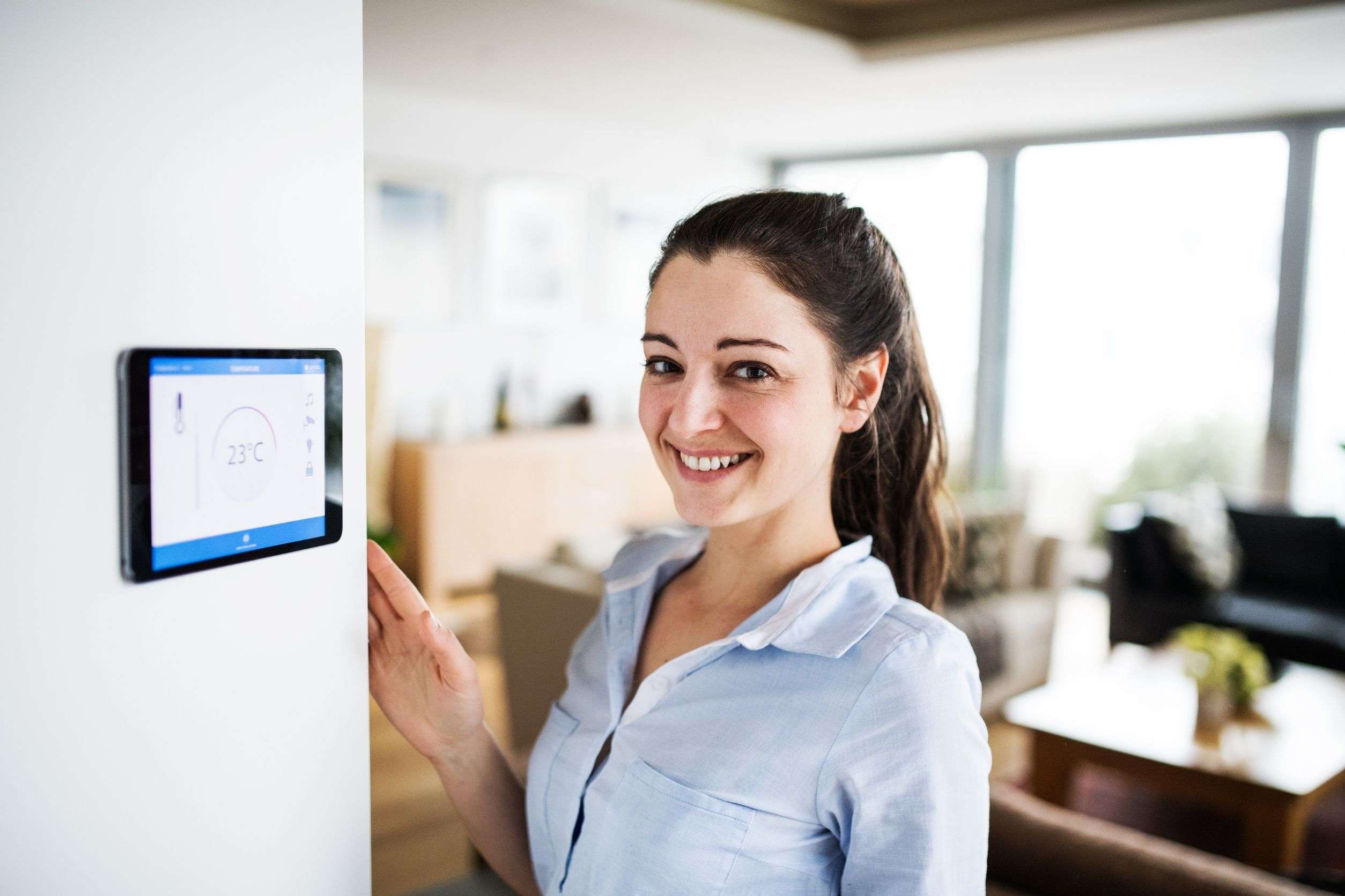 woman standing next to a smart thermostat