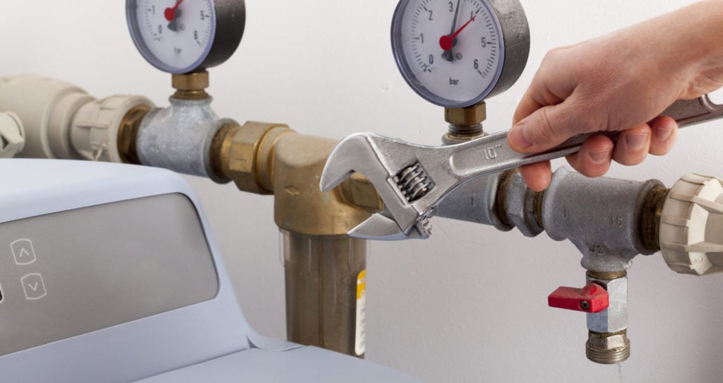 plumber hand using wrench to repair water softener